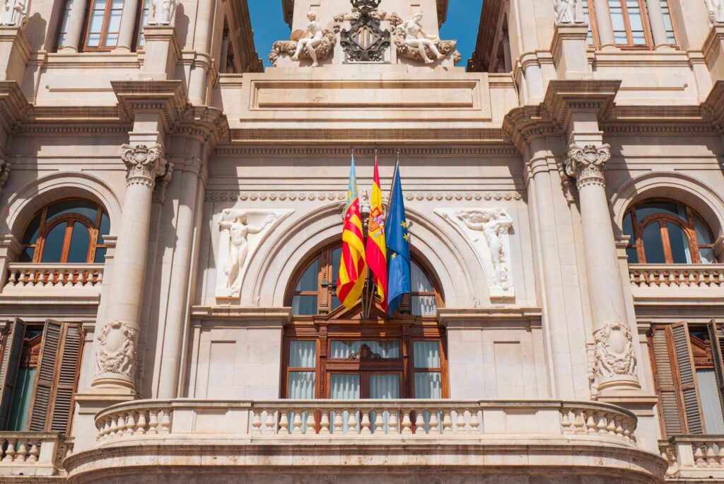 Stunning facade of Valencia City Hall with flags under a clear blue sky.